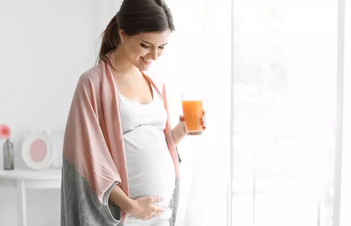 Беременная женщина пьет морковный сок