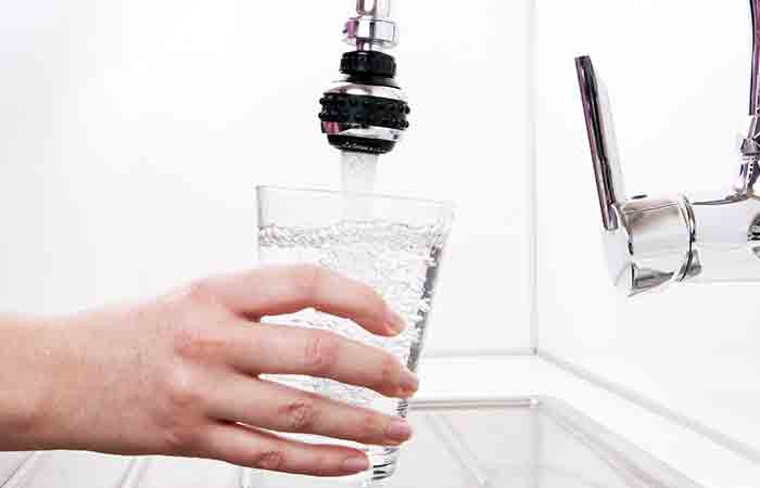 Рука со стаканом фильтрованной водопроводной воды
