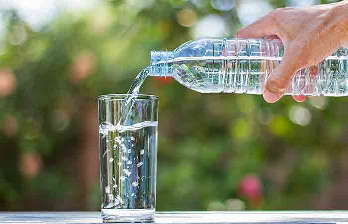 Рука наливает минеральную воду в стакан из бутылки с водой