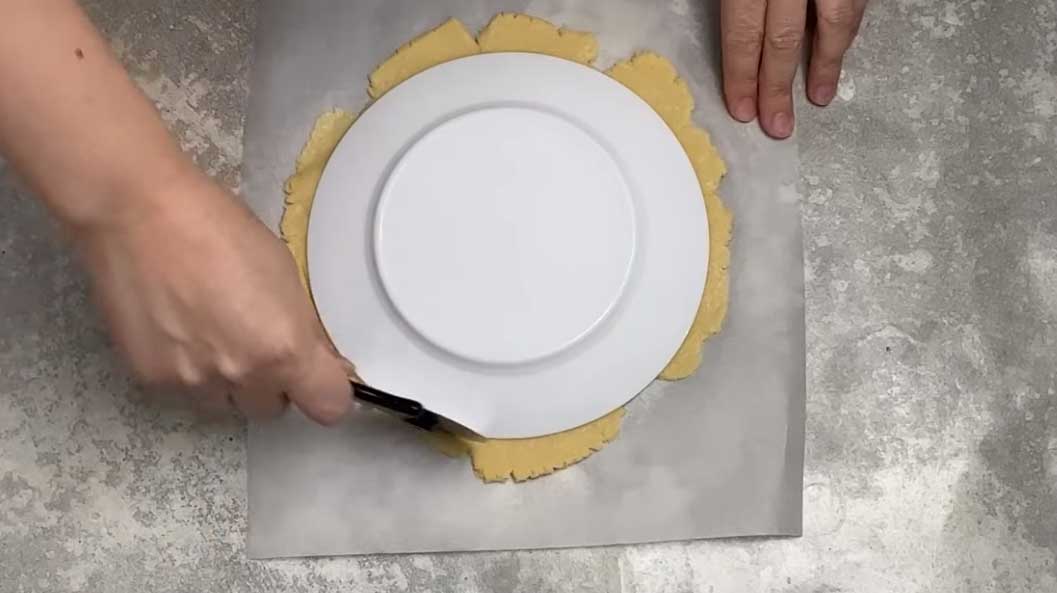 Раскатайте тесто и по контурам тарелки вырежьте круг