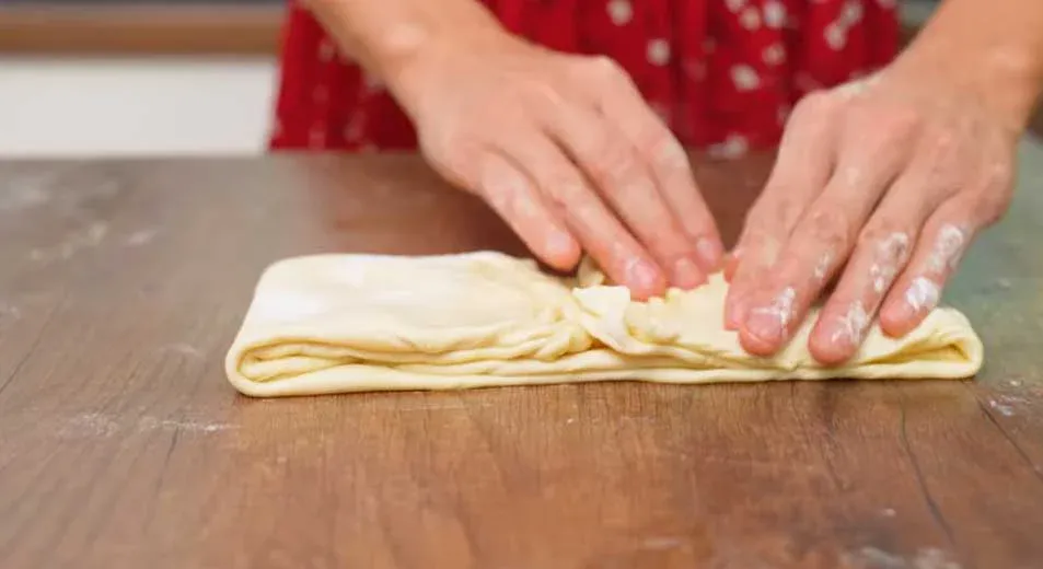 Сложите тесто, перемазывая слои маслом