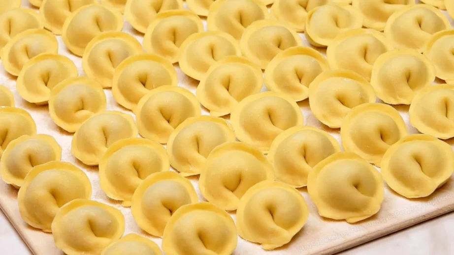 Аппетитные домашние пельмени с сочной начинкой на деревянном столе, мука, яйца, раскатанное тесто, руки в муке, уютная кухня, естественное освещение