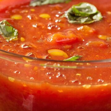 Густой холодный суп гаспачо в прозрачной чаше с оливковым маслом и базиликом, яркий кулинарный концепт.