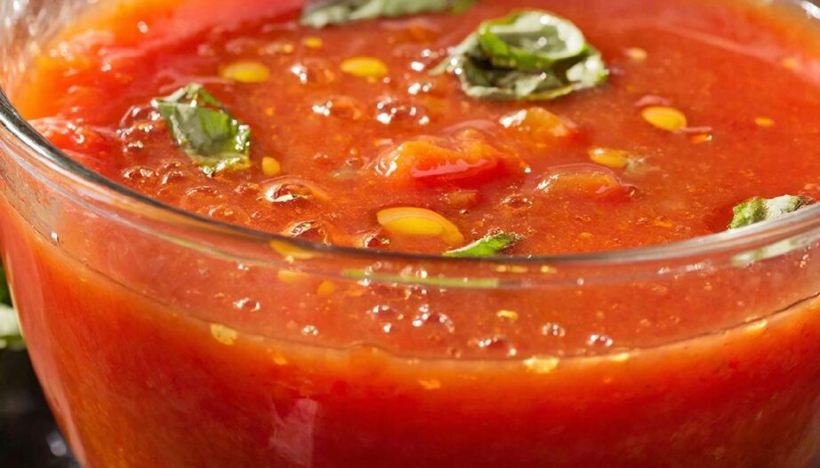 Густой холодный суп гаспачо в прозрачной чаше с оливковым маслом и базиликом, яркий кулинарный концепт.