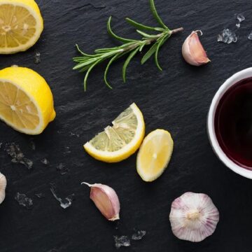 Набор натуральных ингредиентов для маринада: лимон, вино, зелень и киви на темном фоне.