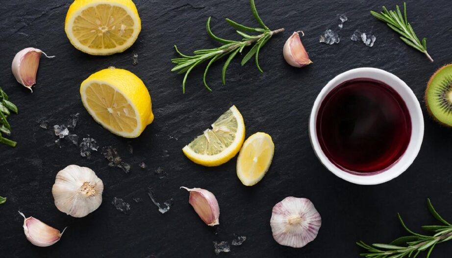 Набор натуральных ингредиентов для маринада: лимон, вино, зелень и киви на темном фоне.